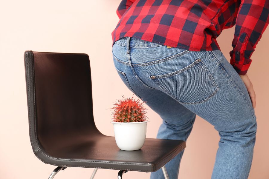 Man Avoiding Sitting on Chair with Cactus – Symbolizing Pain and Discomfort from Hemorrhoids